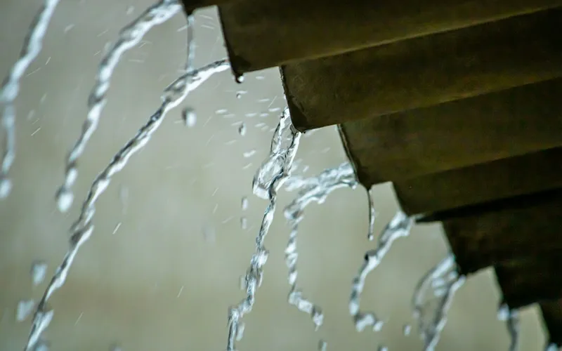 Água da chuva escorrendo pela borda do telhado