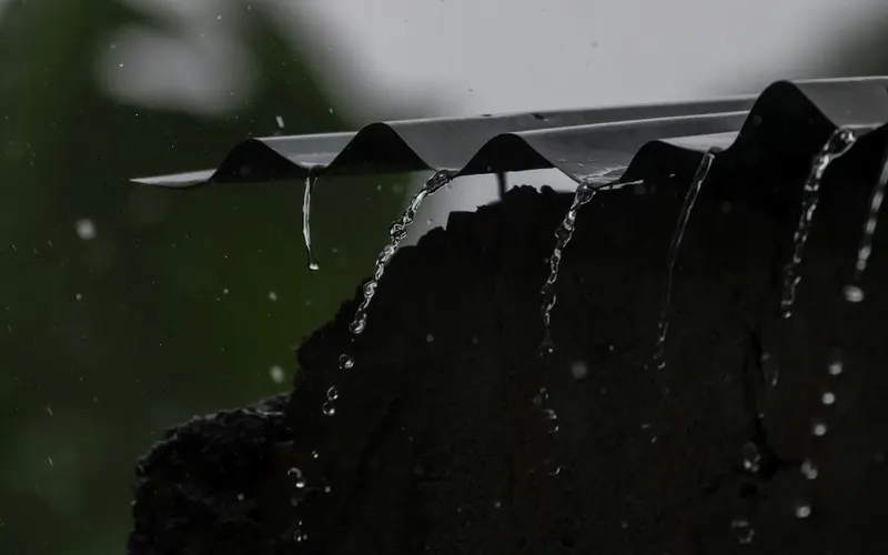 Água da chuva transbordando da borda de um telhado