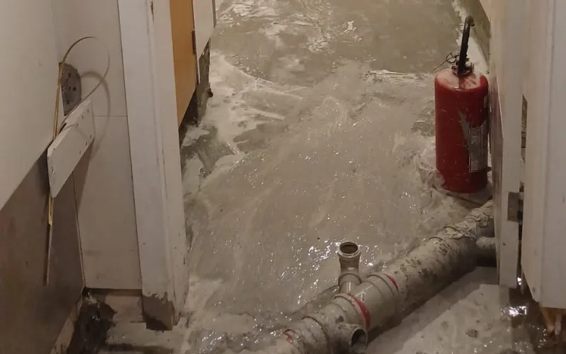 Piso aberto com tubulação exposta durante diagnóstico, em obra da Hidequel
