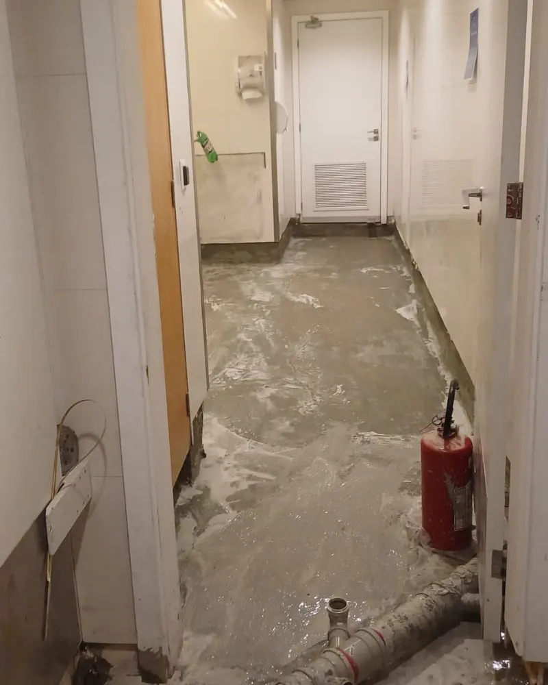 Piso aberto com a tubulação exposta durante o diagnóstico, em obra da Hidequel