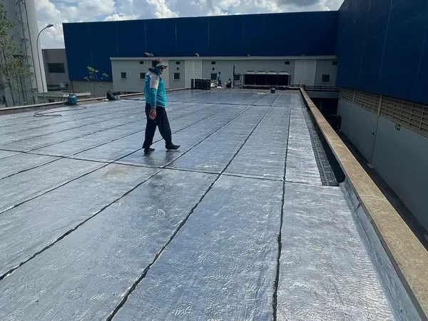Funcionário caminhando sobre a manta aluminizada recém-aplicada em laje